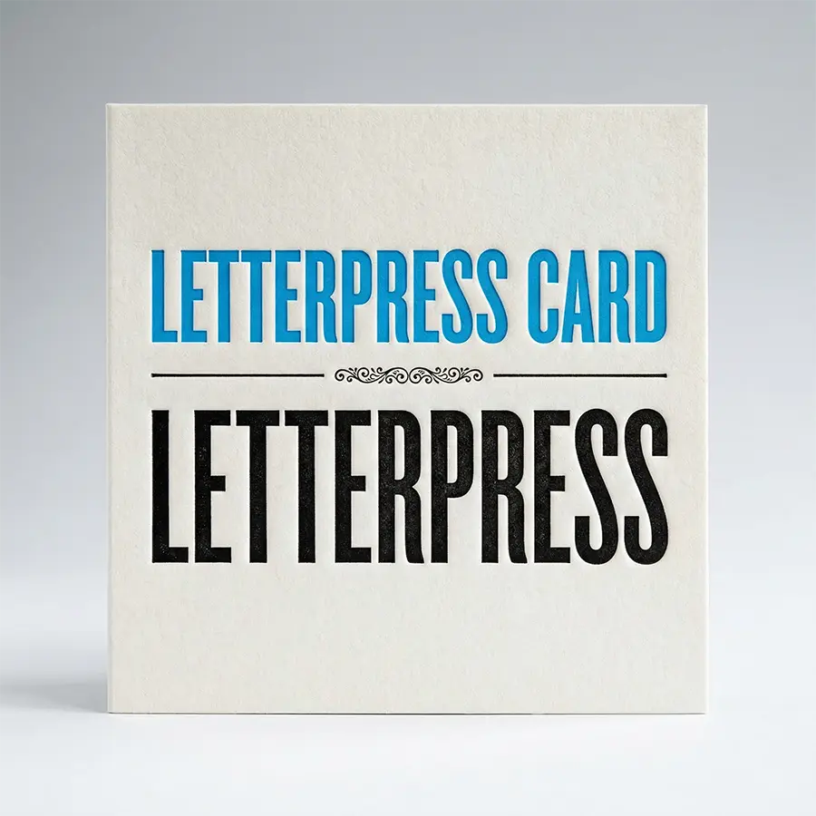 Extreme close-up of a white cotton paper postcard showing the deep debossed indentation of letterpress ink into the soft, textured fibers.