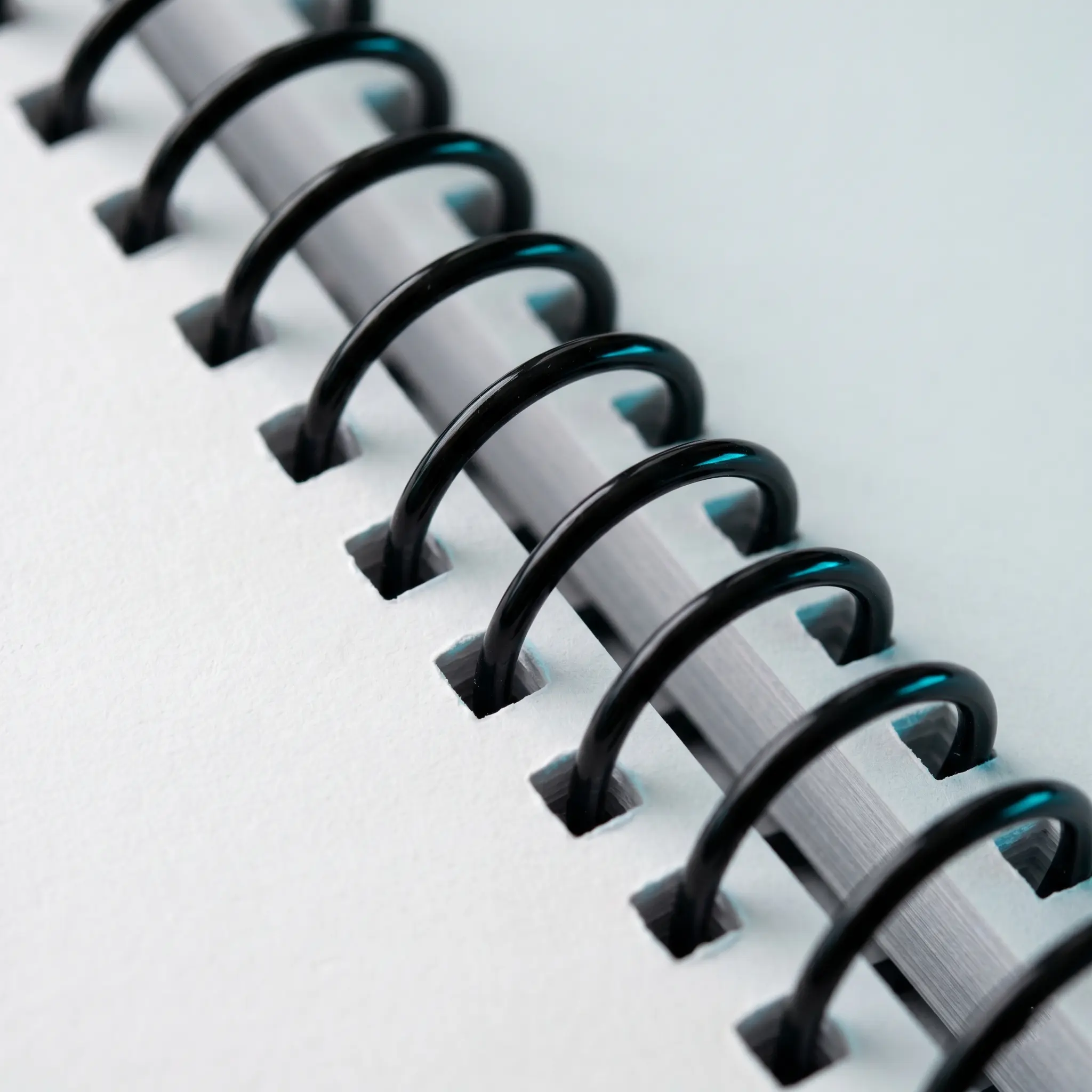 Coil Binding NYC, black plastic coil rings close-up for lay-flat documents Black plastic coil rings on the document spine for coil binding NYC, creating a durable spiral bound lay-flat document look.