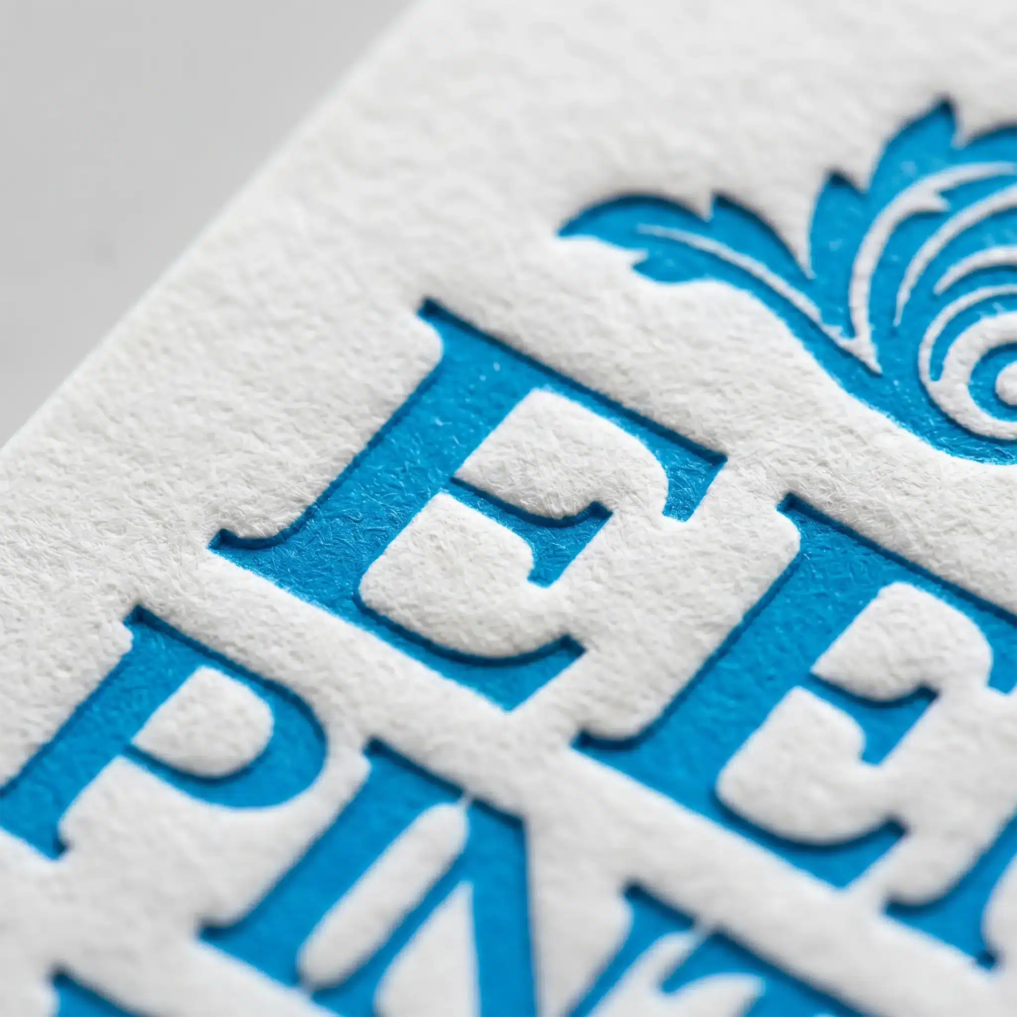 Finishing Services 7 Close-up of classic letterpress printing with blue ink pressed into textured paper, showing crisp raised letter edges and fine impressions.