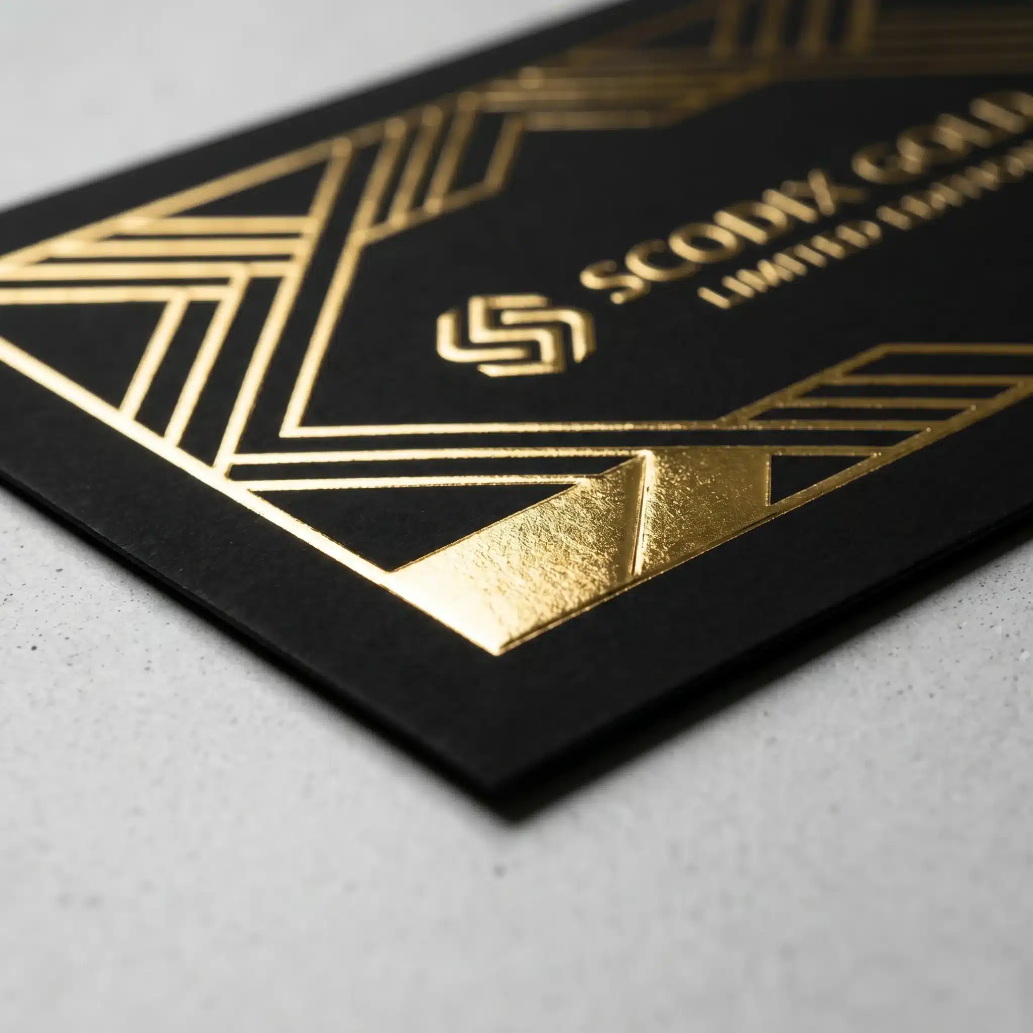 Soft-Touch Scodix Foil on black card, gold foil geometric accents Close view of soft-touch Scodix foil on black stock with gold foil geometric lines and textured reflective accents.