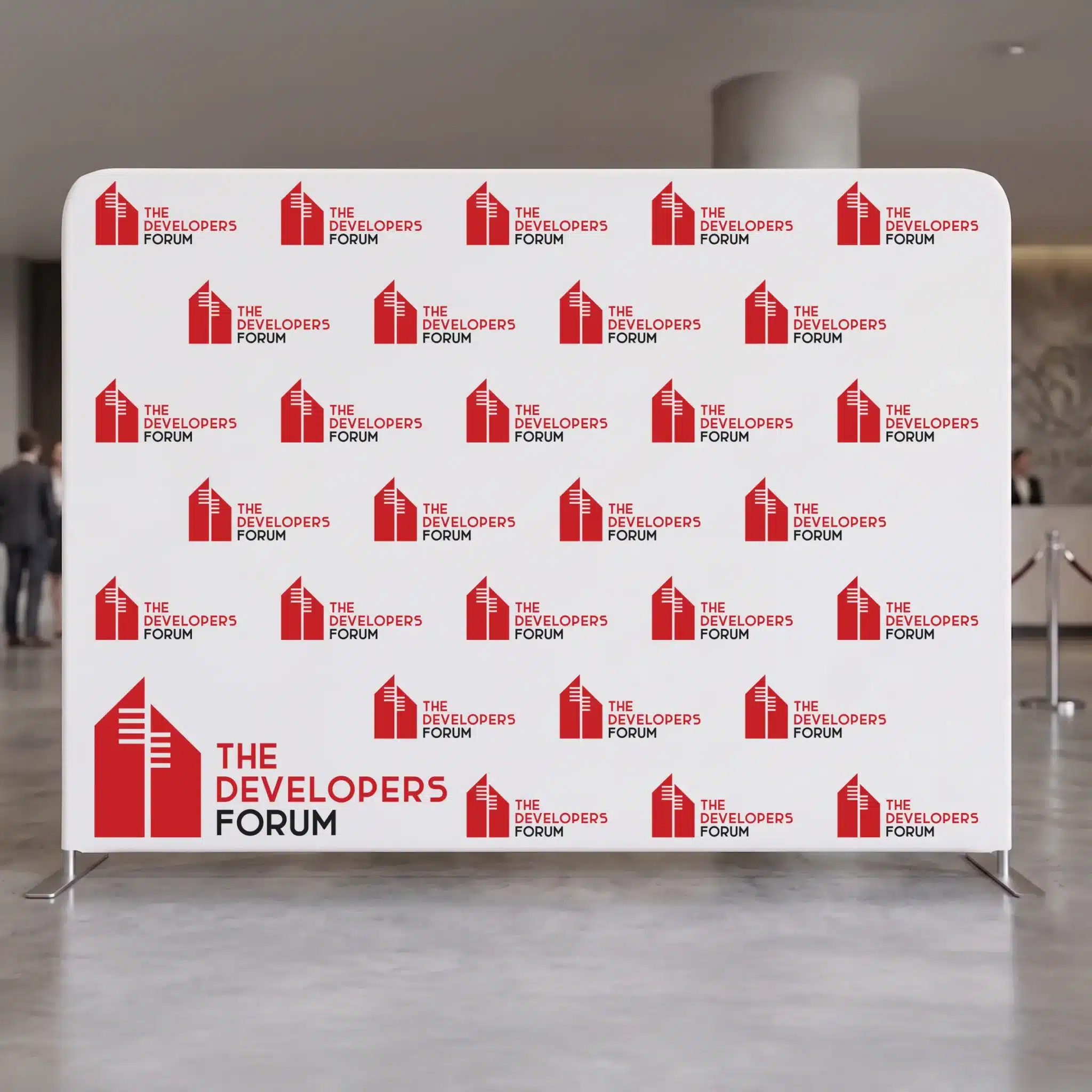 The Developers Forum branded banner stand, repeated logo backdrop for events A repeating The Developers Forum logo pattern covers a white banner stand in a lobby, creating branded event decor with red and black graphics.