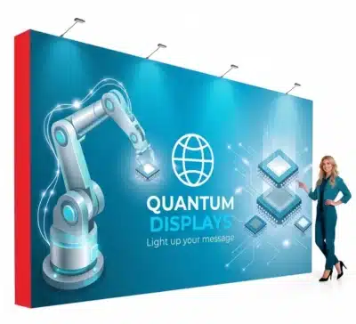 A large blue Quantum Displays trade show backdrop shows a robotic arm, digital circuits, and a standing woman.